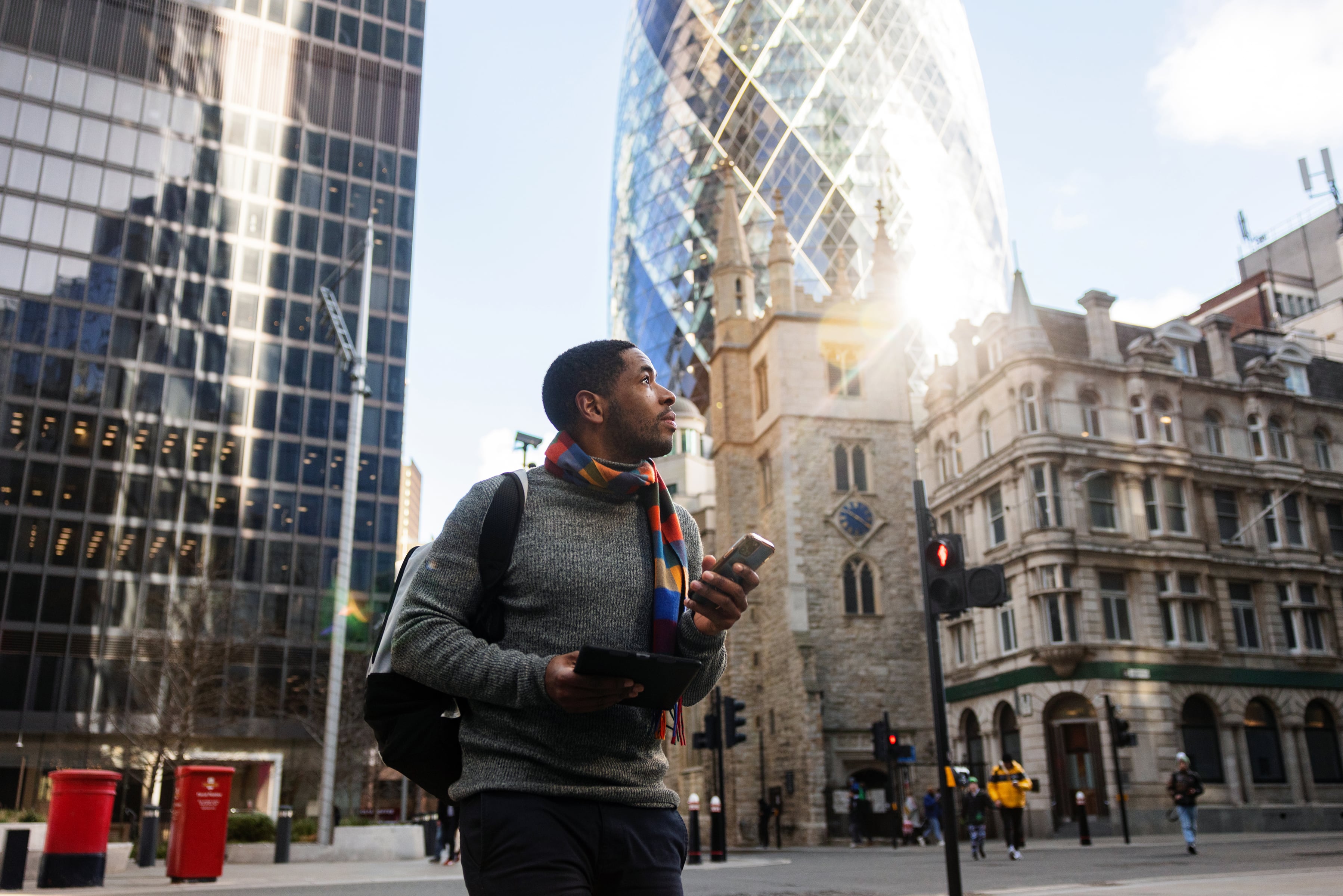 Man holding a mobile phone, crossing the street while considering EOR services in the U.K.