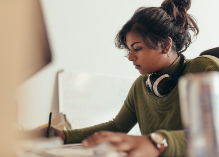 Indian woman writing on paper at her desk