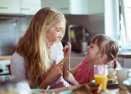 Mother and young daughter laughing and enjoying quality time together in their home kitchen