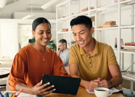 Two professionals smiling while looking at an iPad