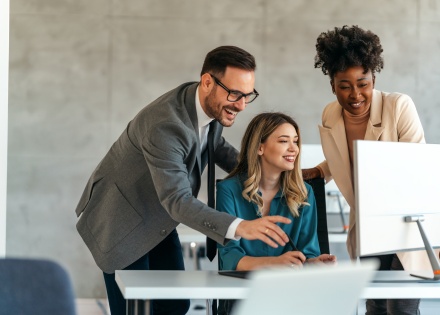 Colleagues showing another colleague how to send crypto payments via desktop computer
