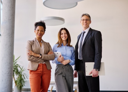 Three coworkers pose for a photo in an office