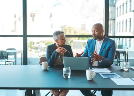 Global payroll managers discussing how currency fluctuations affect payroll