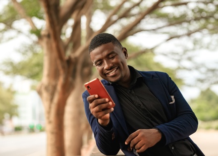 Man smiling and texting on his phone in Nigeria