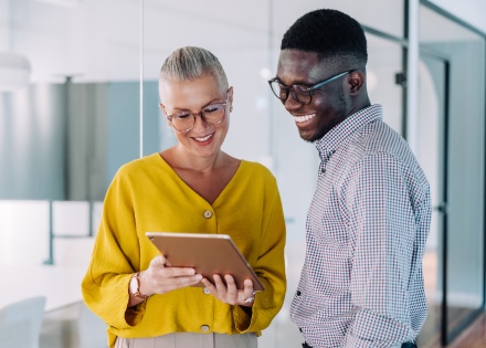 Two colleagues using a digital tablet and discussing payroll tax in Estonia