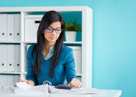 Young businesswoman with glasses calculating payroll taxes in Malta