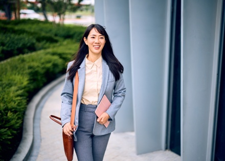 Businesswoman walking outside of office building in Cambodia holding a tablet