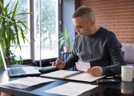 Man using a calculator while reviewing payroll taxes in the Cayman Islands