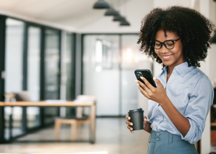 Smiling curly-haired businesswoman using smartphone in office in Congo