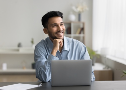 Smiling man sitting at a desk with his laptop in Malaysia