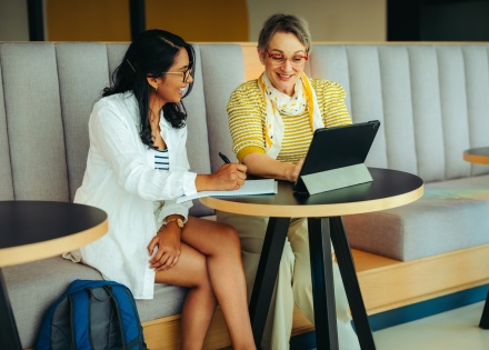 Two women together using a digital tablet discussing payroll taxes in Panama
