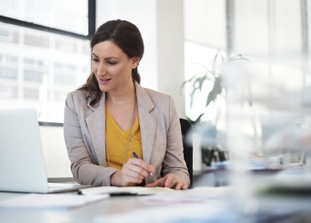 Woman making notes at her desk while using her laptop in Afghanistan