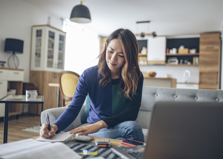 Young woman at home doing her payroll taxes in Guam