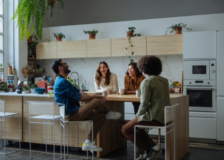 Cheerful friends laughing and sitting in a modern kitchen