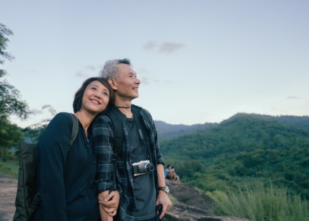 Happy Asian couple hikers on top of a mountain