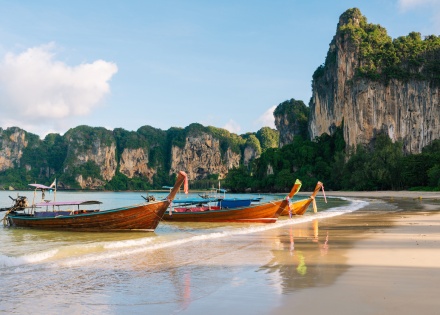 Longtail boats on the beach by Krabi Cliffs in Thailand