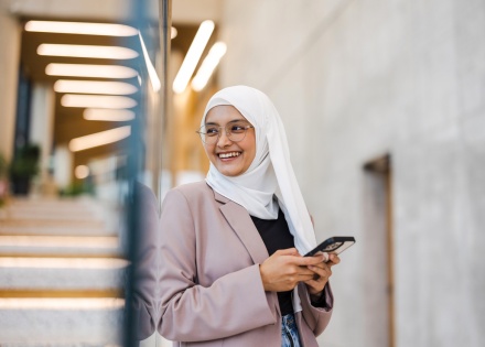 Smiling young woman using smartphone at work