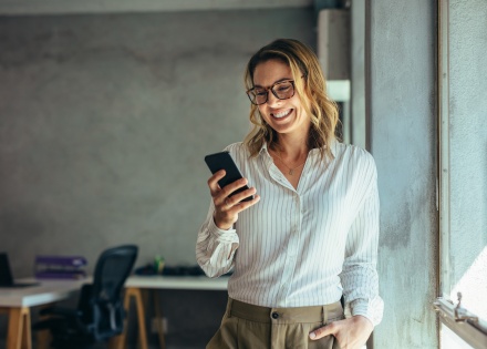 Smiling businesswoman using phone in office