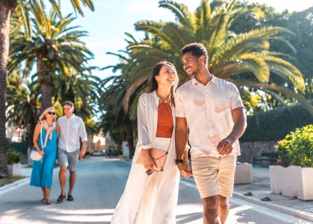 Two couples on holiday in Croatia enjoying a walk along a palm tree-lined promenade