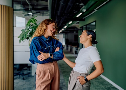 Two women colleagues laughing and talking about workplace culture in Ghana