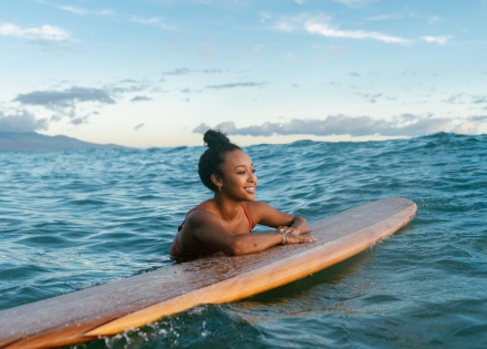 Surfer resting on her surfboard while enjoying Nicaragua’s public holidays