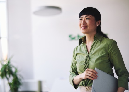 Businesswoman holding a laptop and looking away, smiling