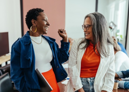 Two colleagues laughing in a vibrant and colorful workplace