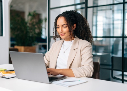 Curly haired woman using laptop while sitting at her workplace in South America