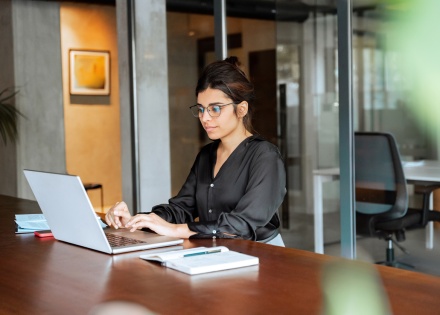 Female graphic designer sitting at desk working on laptop