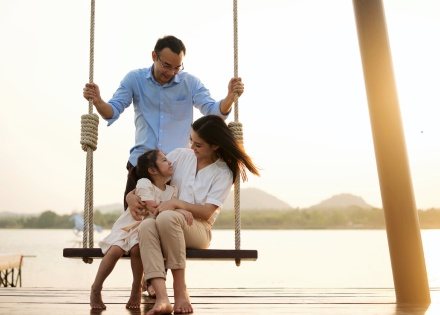 Happy family swinging on dockside swingset in Costa Rica