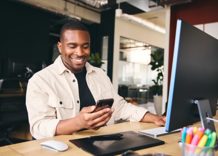 Male bookkeeper working in an office and looking at his phone