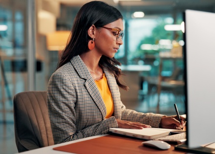 Female paralegal at a law office writing in a notebook at her desk