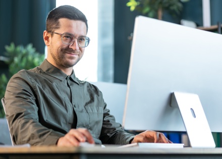 Payroll processor typing on a desktop computer in an office