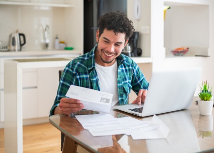 Smiling young man working on his payroll taxes in Kuwait