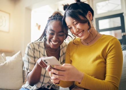 Two women smiling and looking at a phone together