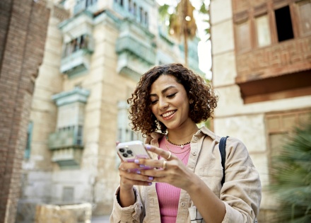 Woman with curly brown hair looking at her smartphone