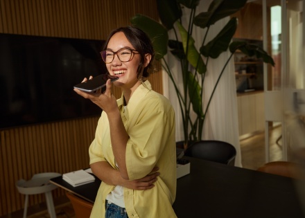 Young businesswoman recording voice message on smartphone