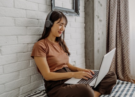 Woman working from home on a laptop while wearing headphones