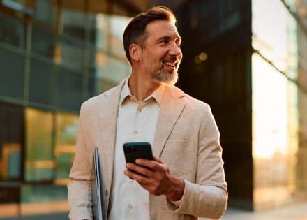 Businessman checking business expenses on his phone while stepping out of the office.