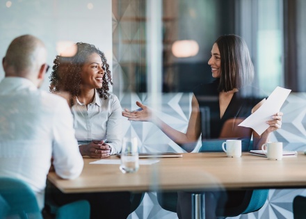 Two woman smiling and talking in meeting table