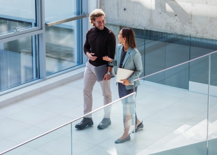 Coworkers chatting while walking through an office, reflecting internal mobility.