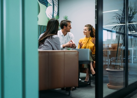Coworkers in a casual office meeting, discussing variable compensation.