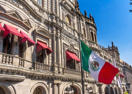 Mexican flag flying in front of buildings on the streets of Puebla, Mexico.