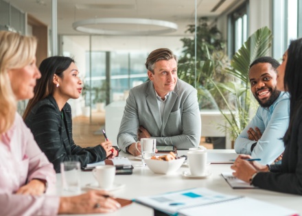 Group of HR leaders discuss the latest industry news around a boardroom table