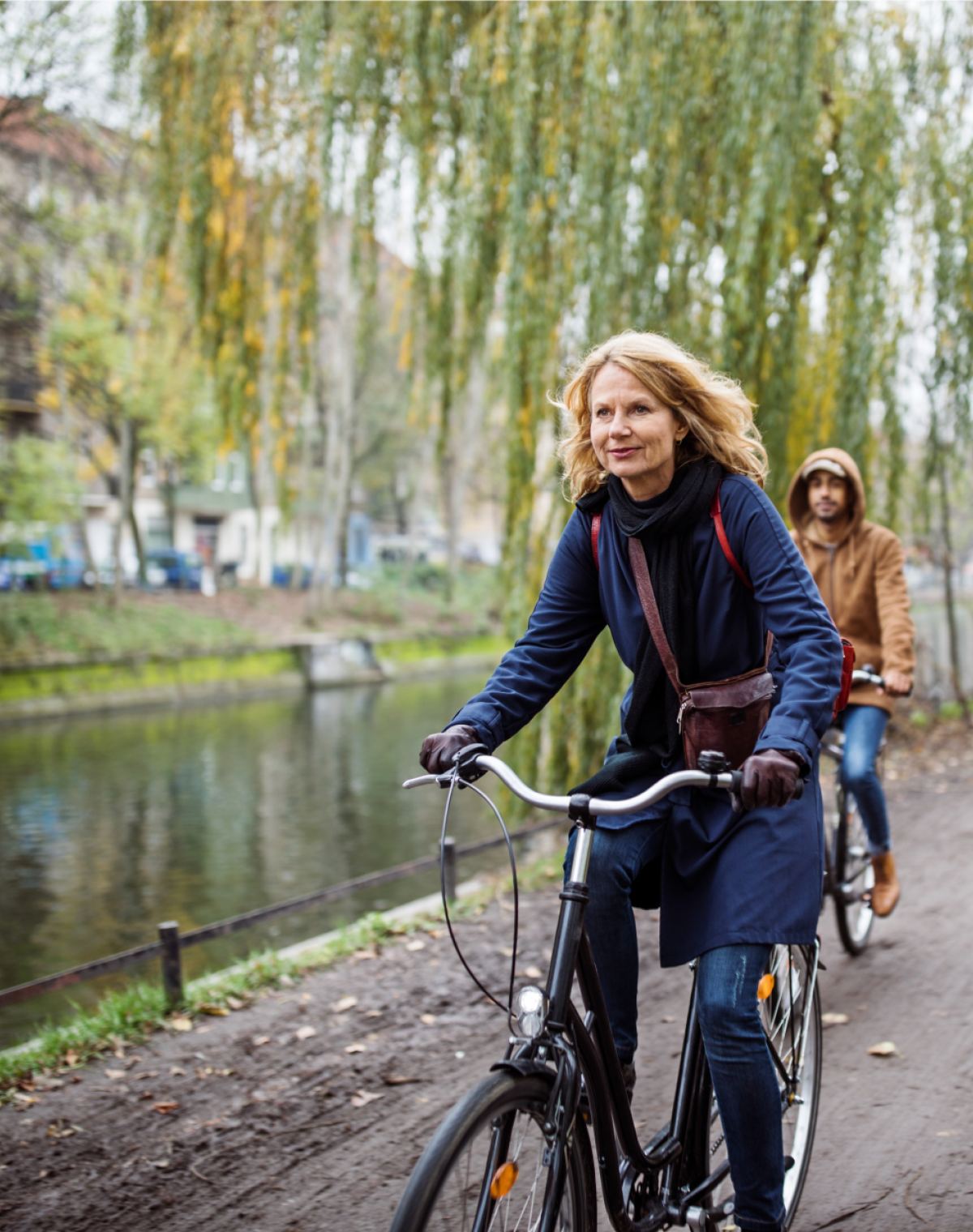 Woman riding bicycle along a river path
