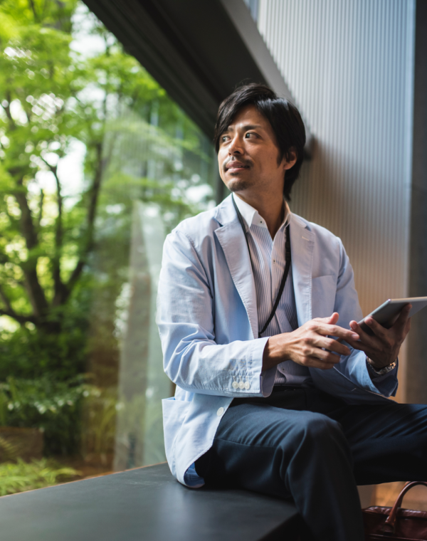 Man on device sitting on window sill looking outside