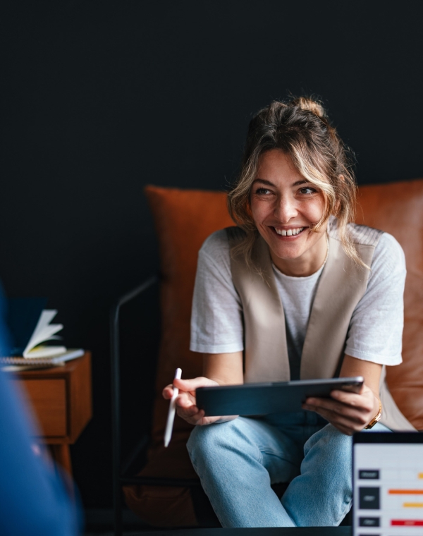 Woman holding tablet during team meeting discussing HR compliance.