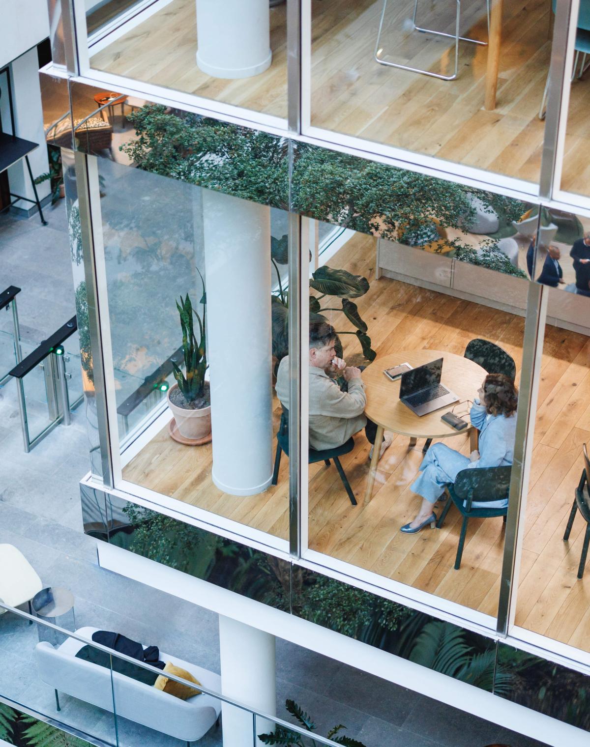 Overhead view of colleagues meeting in a modern office building with glass walls.
