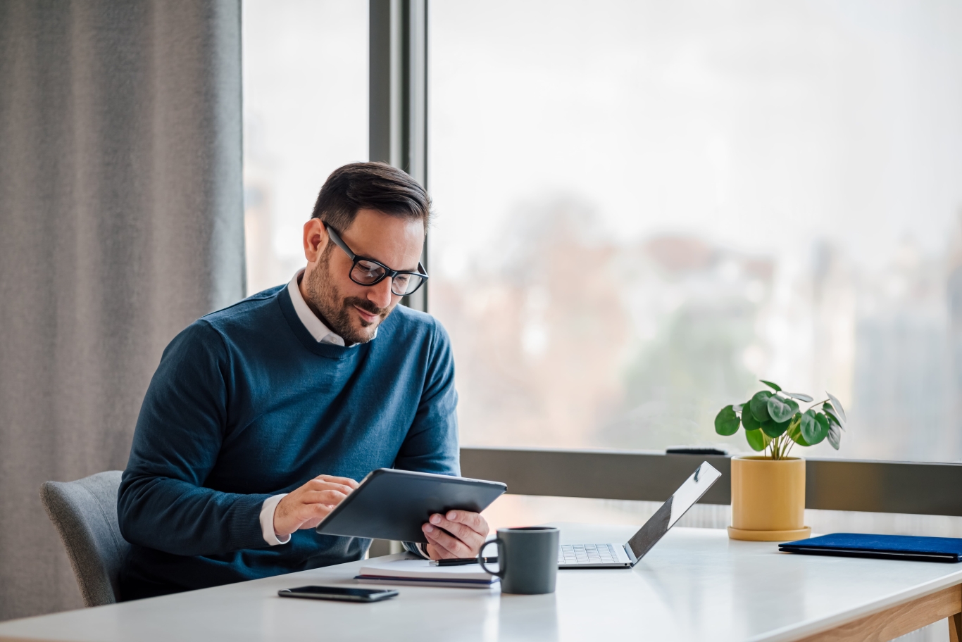 Male employer in office setting reviewing Pebl EOR for consulting firms on tablet.