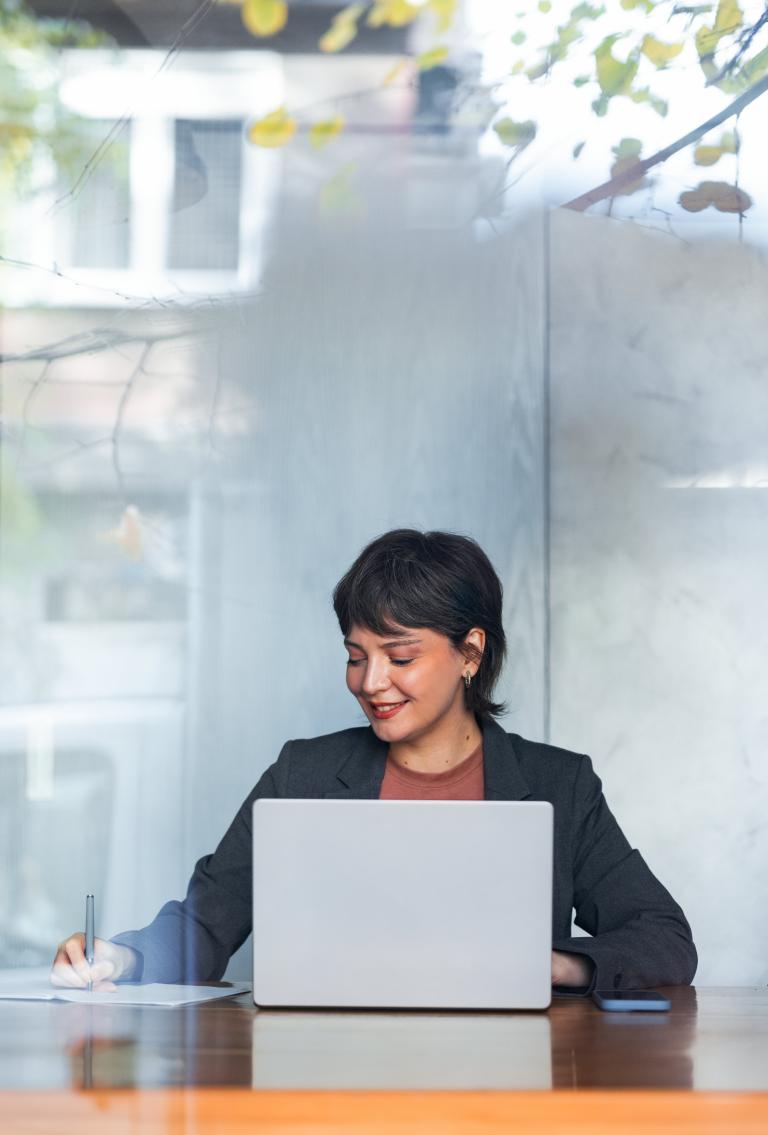 Woman researching and taking notes on an EOR for the retail industry on her laptop.